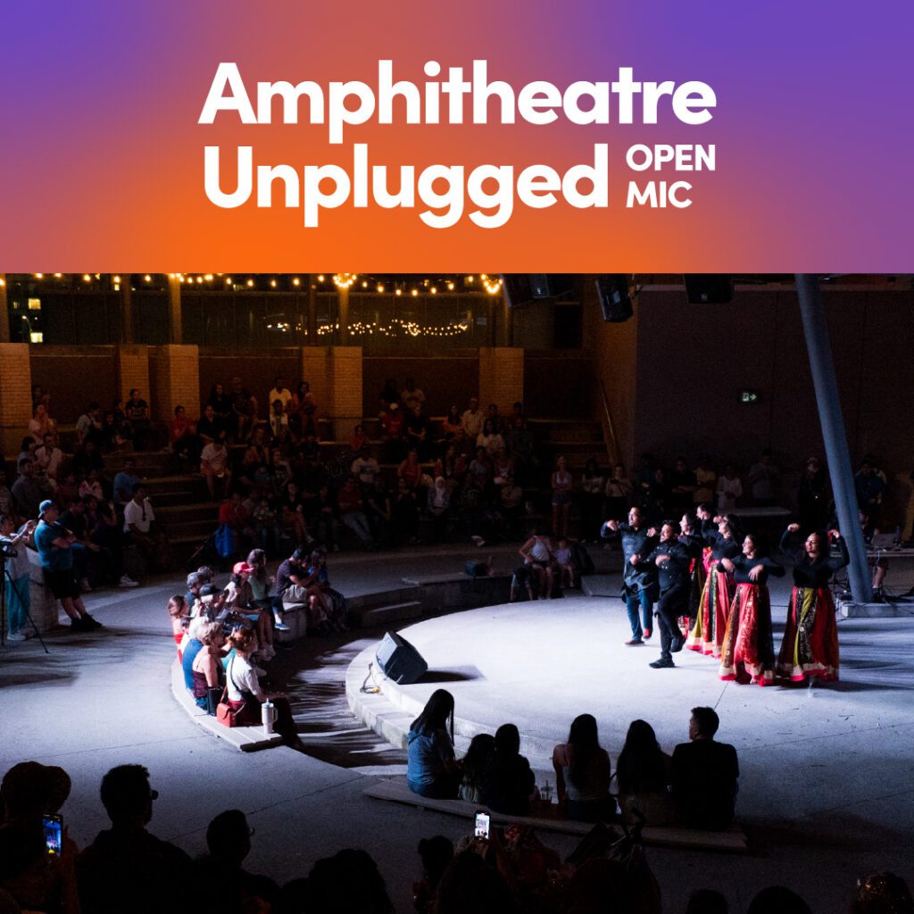 A lively outdoor amphitheatre event at night, with performers in colourful traditional attire dancing on stage while an engaged audience watches. The event title, "Amphitheatre Unplugged Open Mic," is displayed in white text on a gradient background at the top.